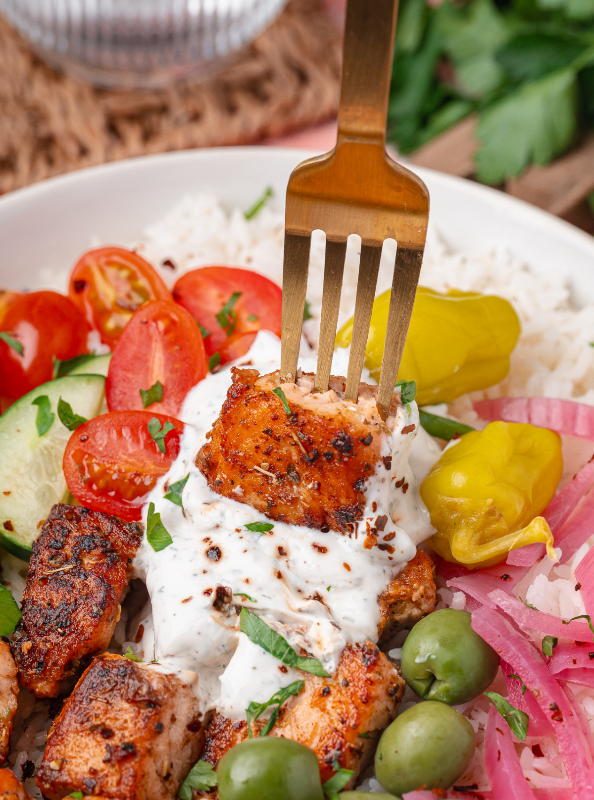 Greek Salmon Rice Bowl with crispy salmon bites topped with yogurt dill sauce, olives, pickled red onions, and fresh vegetables