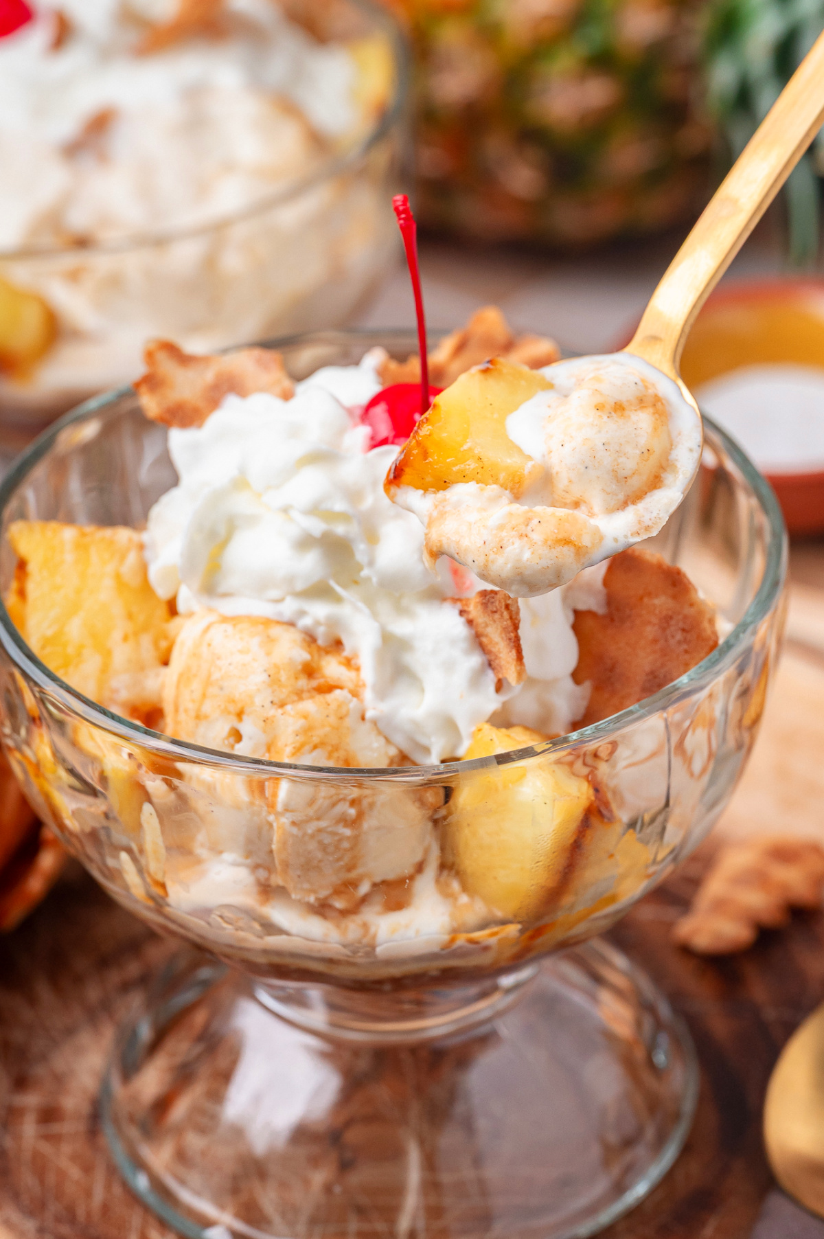 Grilled pineapple sundae with hot buttered rum sauce, vanilla ice cream, whipped cream, and a cherry on top