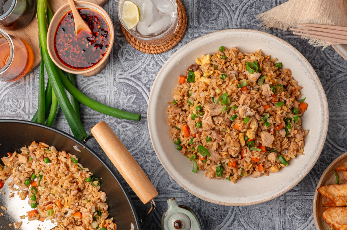 Chicken fried rice with rotisserie chicken, vegetables, and green onions served from a wok and bowl
