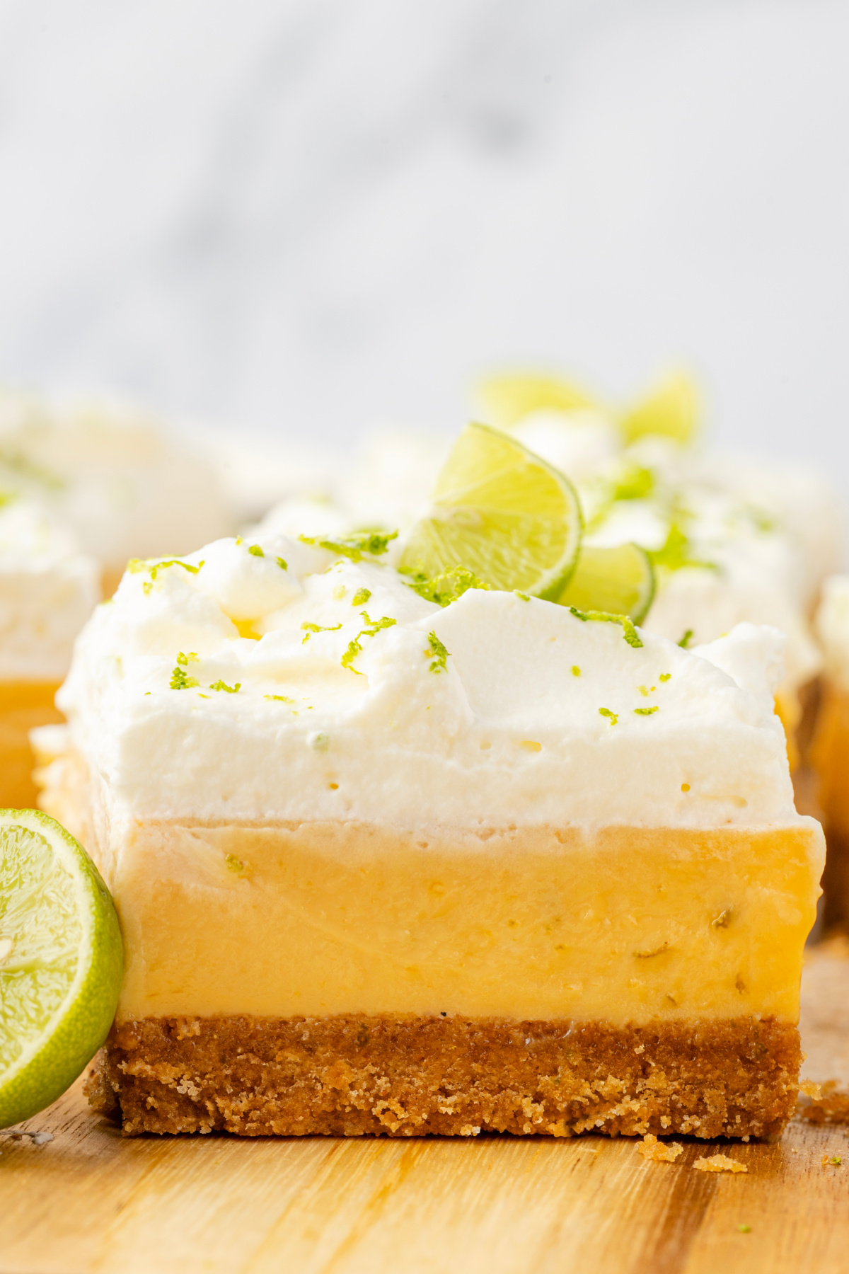 Key lime bars with whipped cream topping, thick custard layer, and graham cracker crust