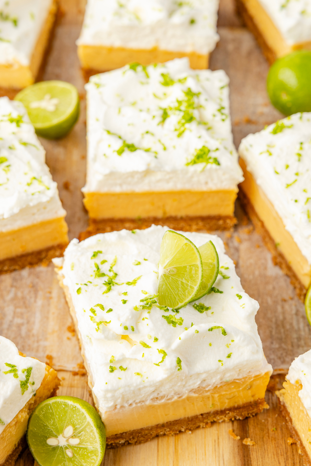 Bakery-style key lime bars cut into squares with whipped cream and fresh lime garnish