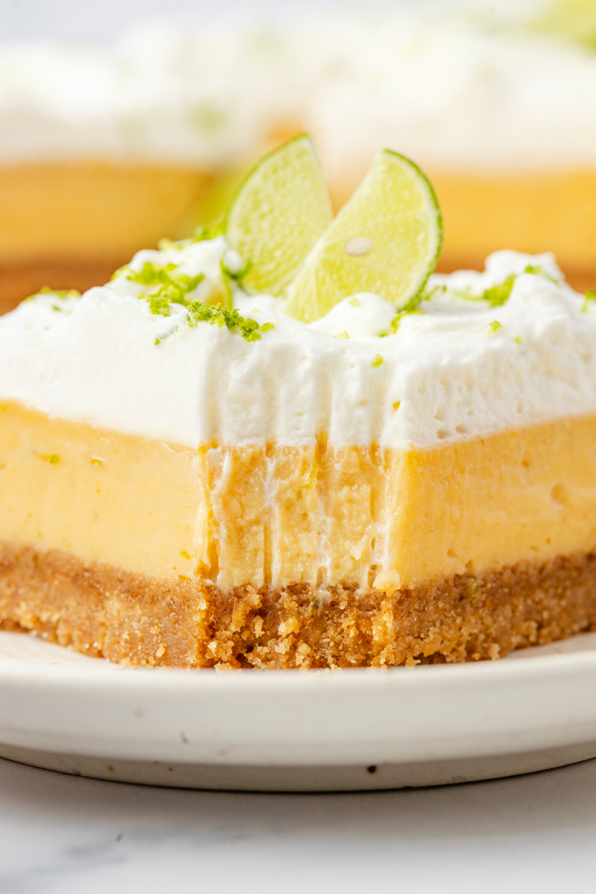 Close-up of thick lime custard slice with whipped cream topping and graham cracker crust