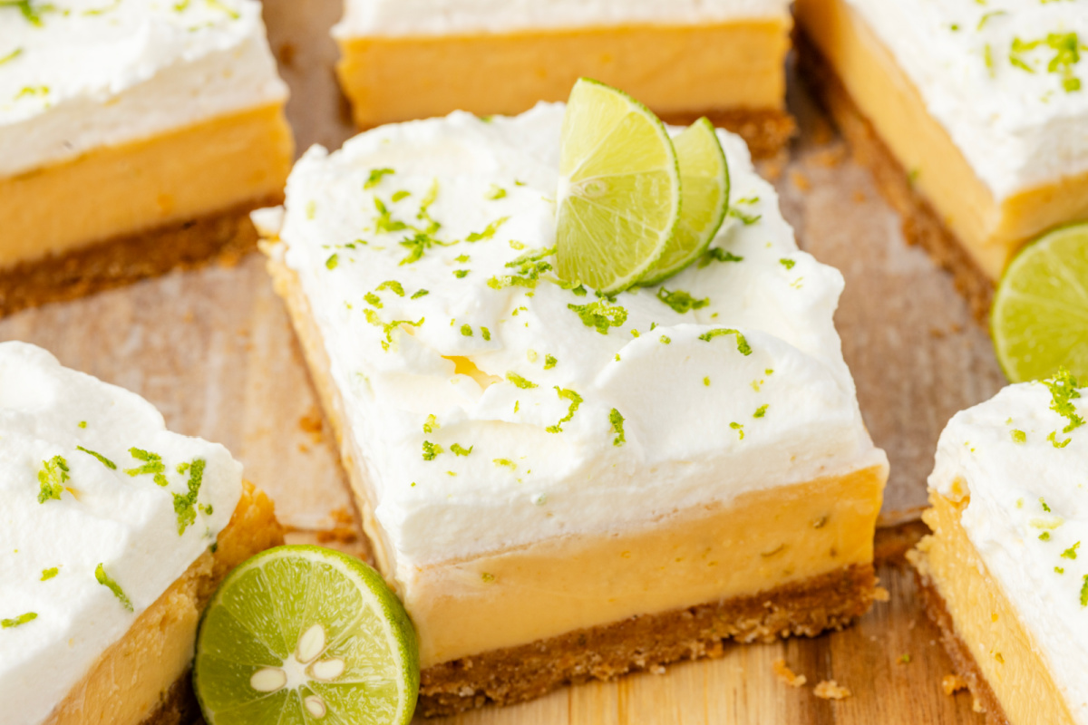 Key lime bars with thick custard filling, whipped cream topping, and fresh lime garnish