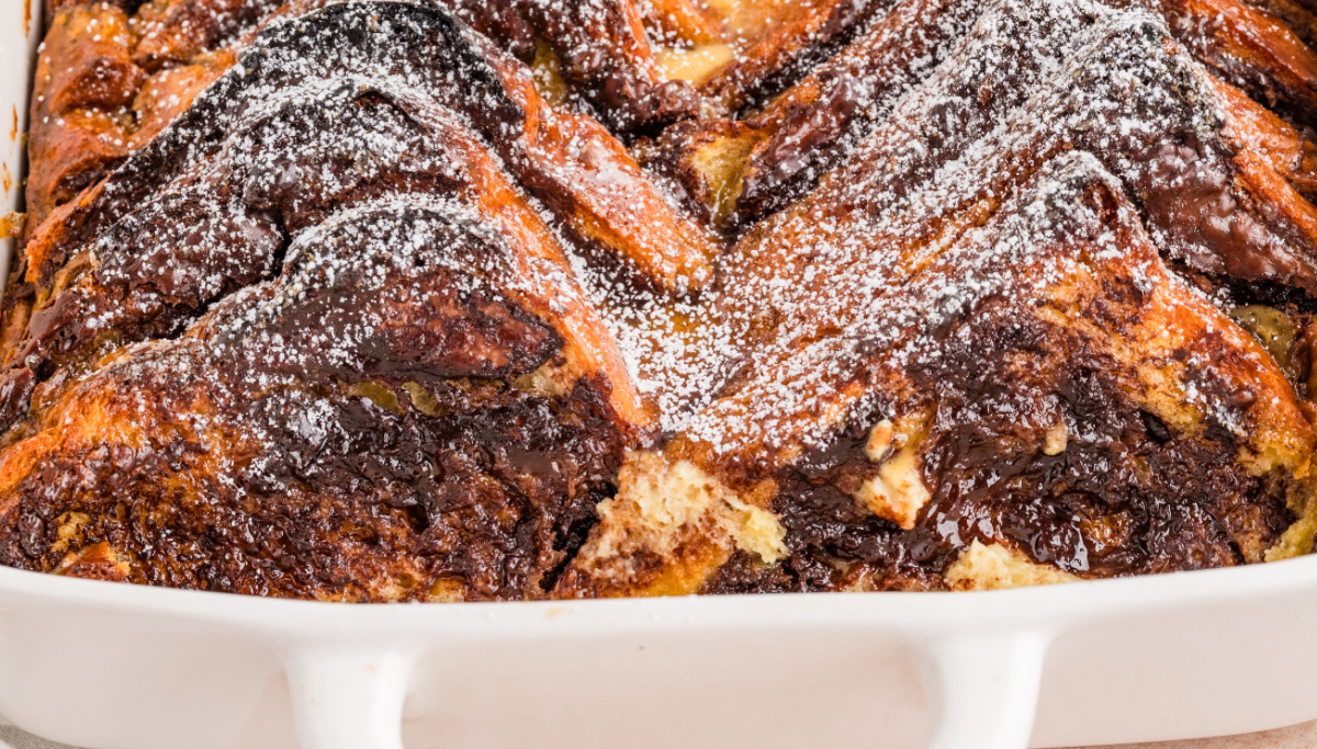 Close-up of baked brioche French toast casserole with melted chocolate hazelnut layers and powdered sugar on top