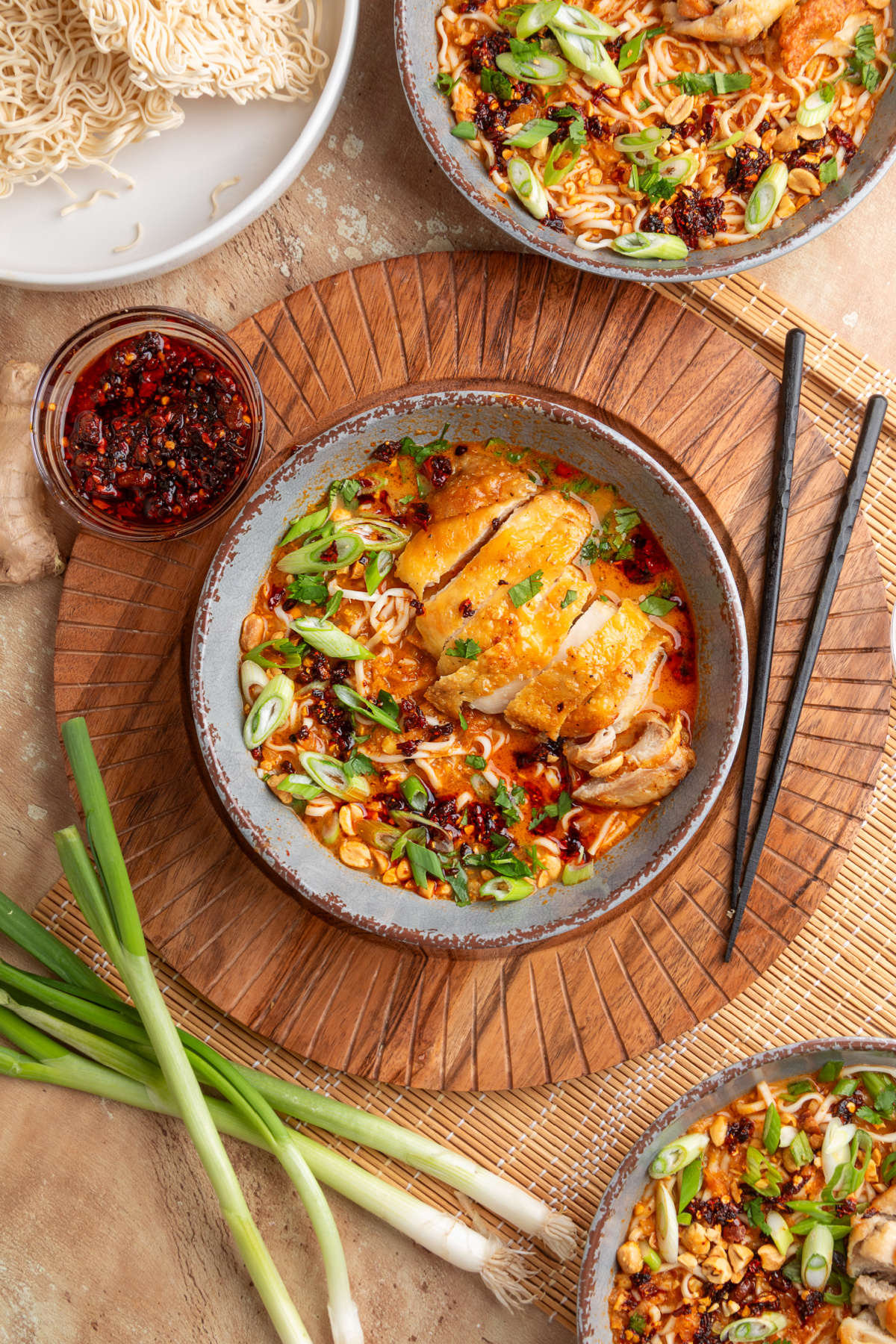 Overhead view of panang curry ramen with crispy chicken, coconut curry broth, ramen noodles, scallions, peanuts, and chili oil