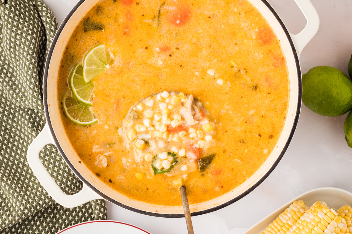 Overhead view of creamy poblano chicken and rice soup simmering with corn and lime slices