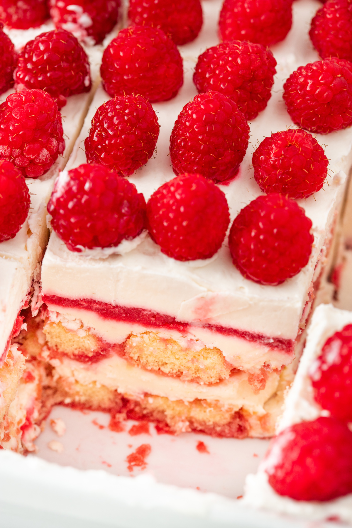 Close-up of berry tiramisu layers with mascarpone cream, raspberry filling, and fresh raspberries on top