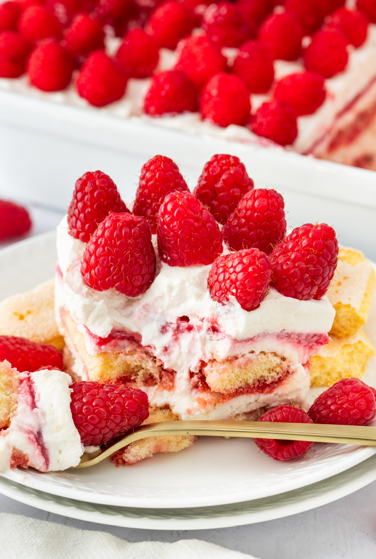 Raspberry tiramisu slice topped with fresh raspberries and layered mascarpone cream