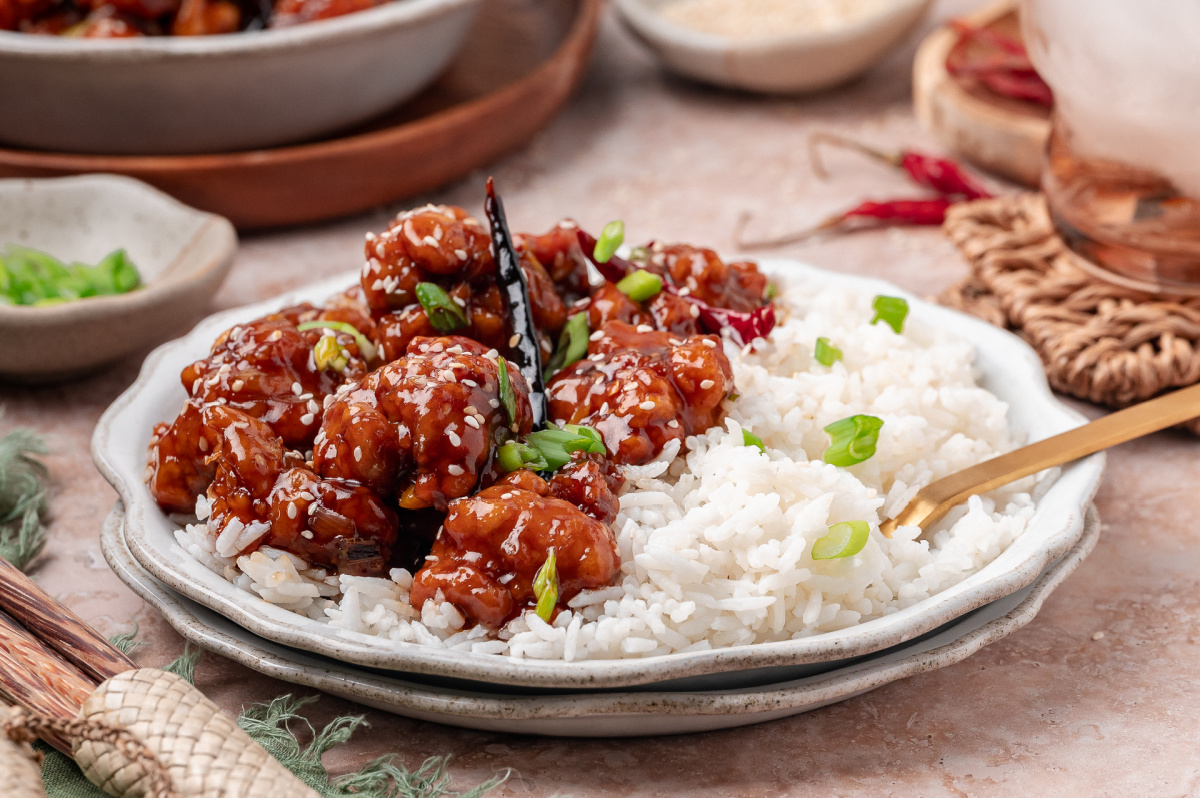 General Tso&rsquo;s chicken served over steamed white rice with scallions and sesame seeds
