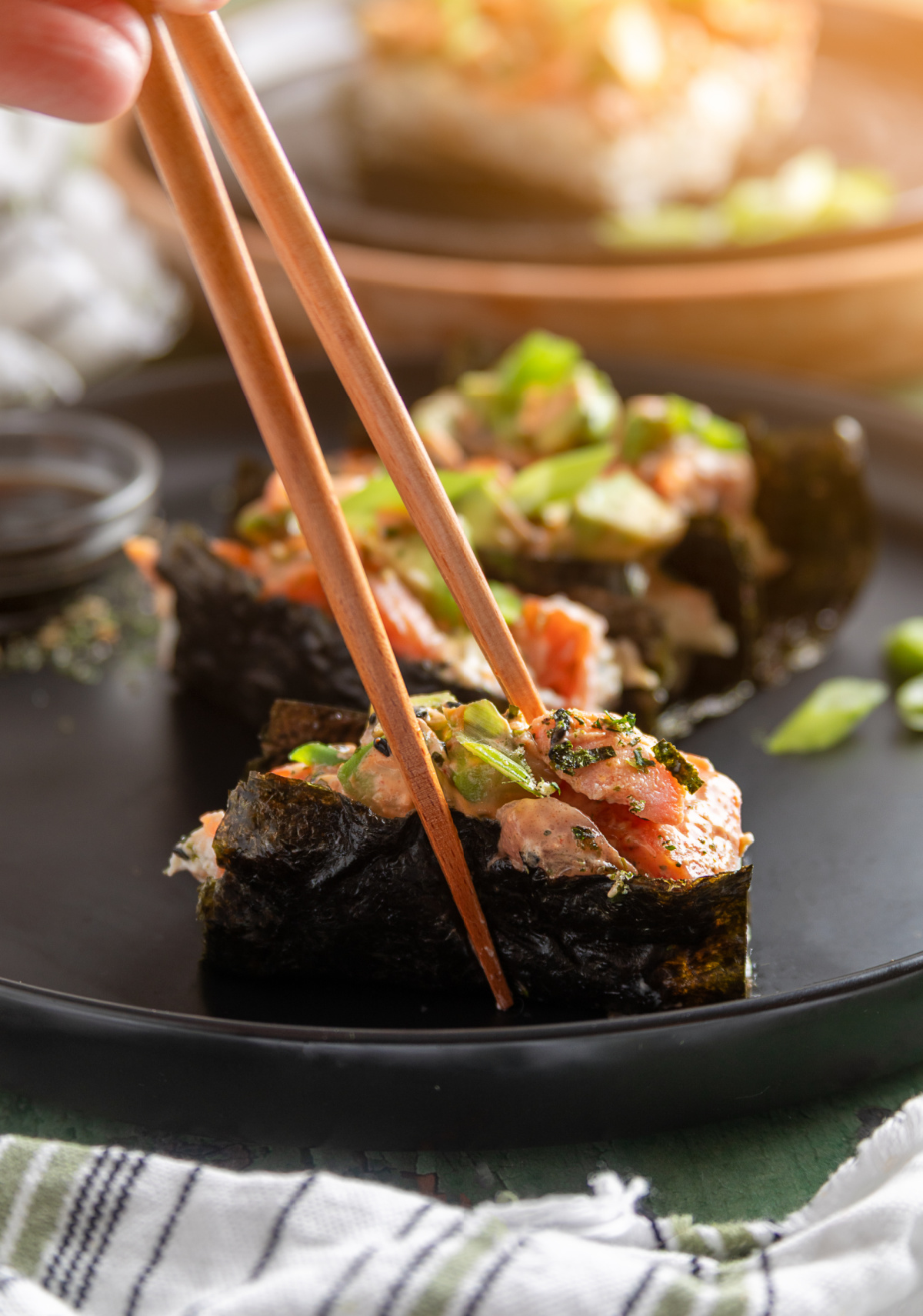 Sushi bake wrapped in nori and lifted with chopsticks