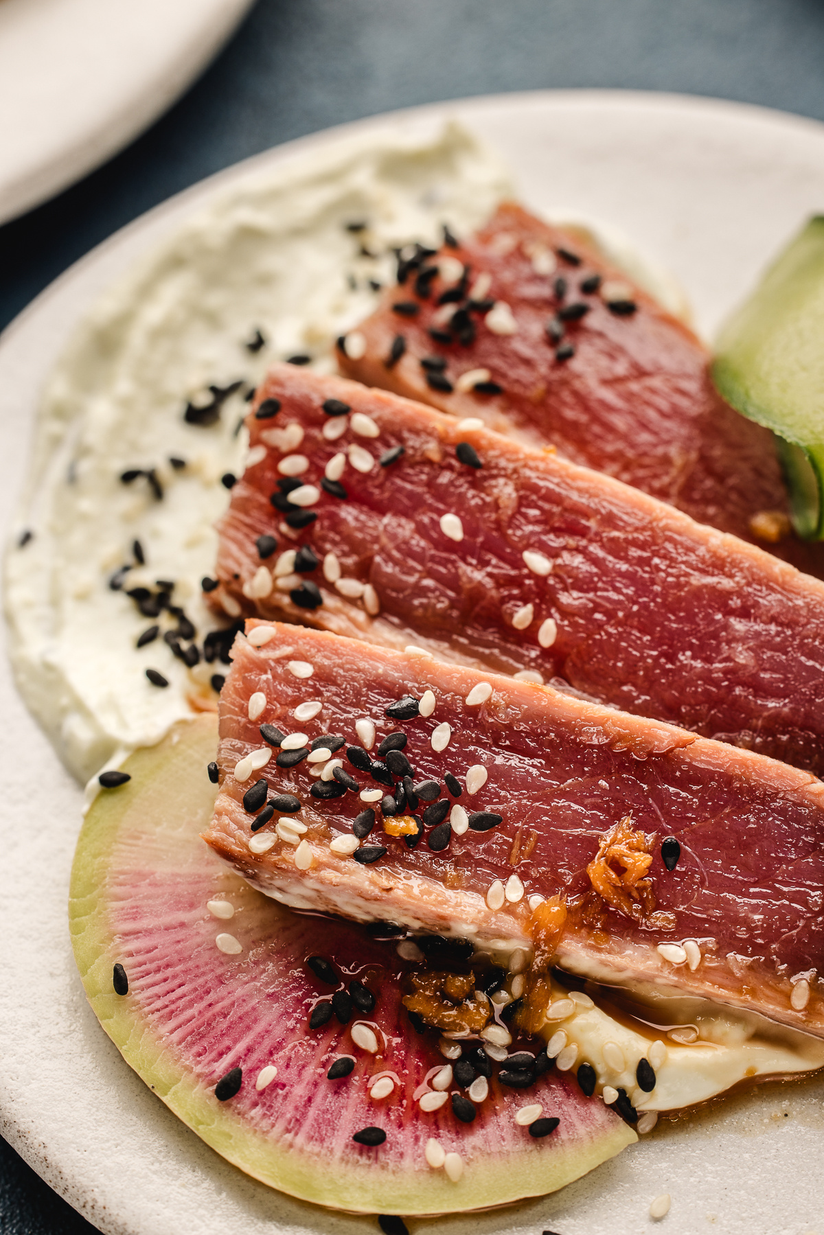 Seared ahi tuna sliced rare with sesame seeds, watermelon radish, and wasabi Greek yogurt smear