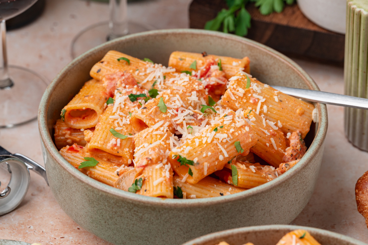 Bowl of creamy Calabrian chili rigatoni topped with Parmesan and parsley