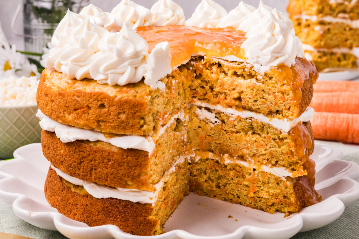 Carrot cake layers with apricot filling and cream cheese frosting on a white cake stand