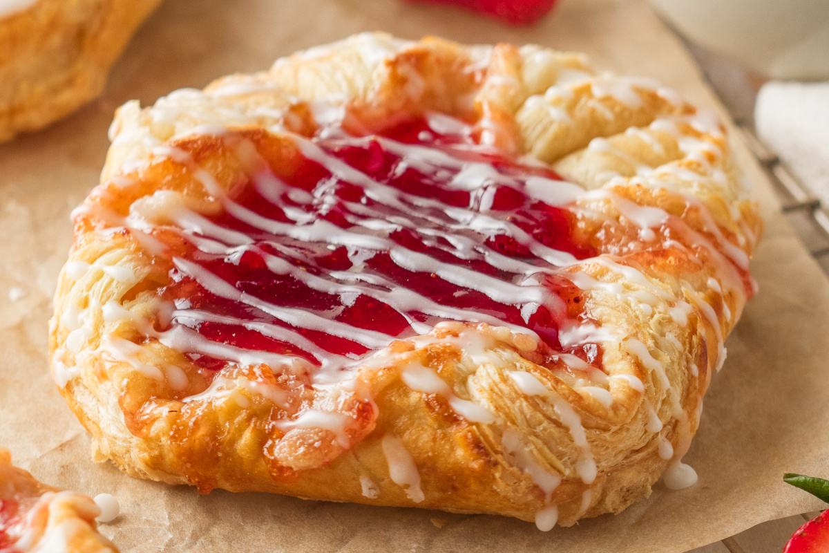 close-up strawberry cream cheese danish with flaky puff pastry layers and glaze drizzle