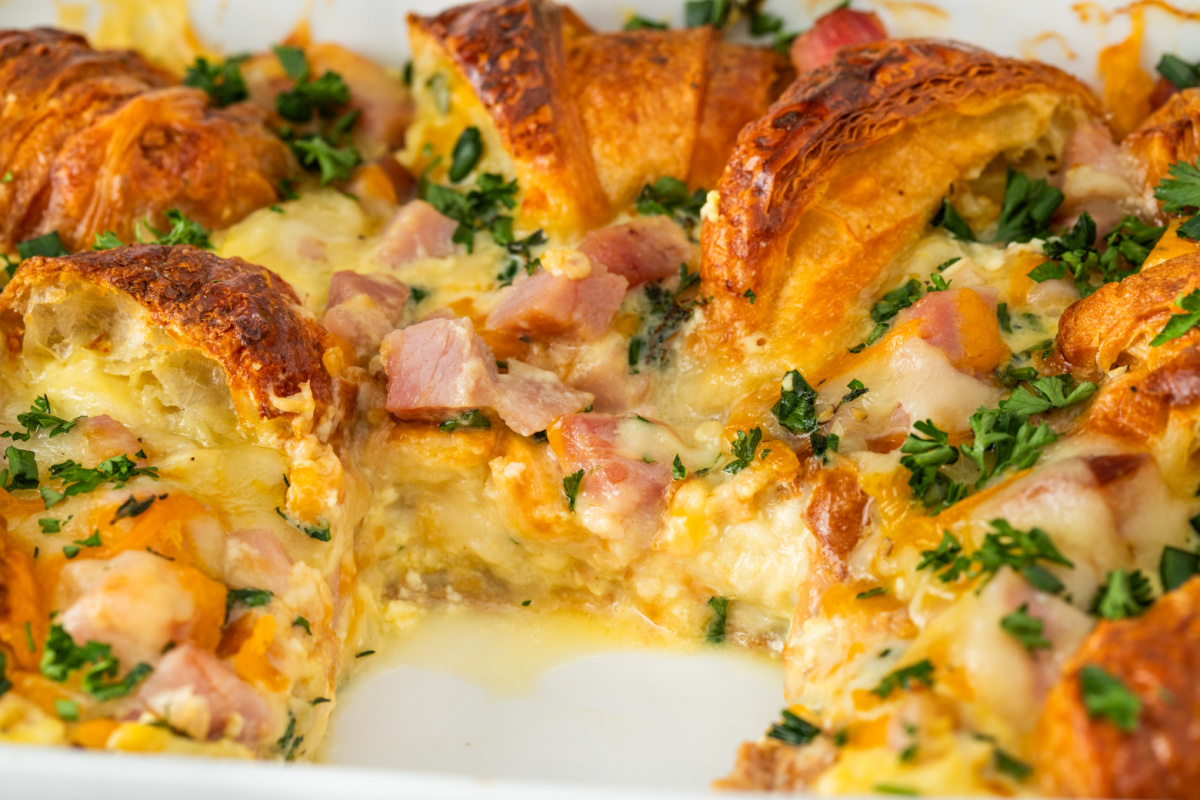 close-up of croissant breakfast casserole with ham, melted Swiss and cheddar cheese, egg custard, and parsley baked until golden