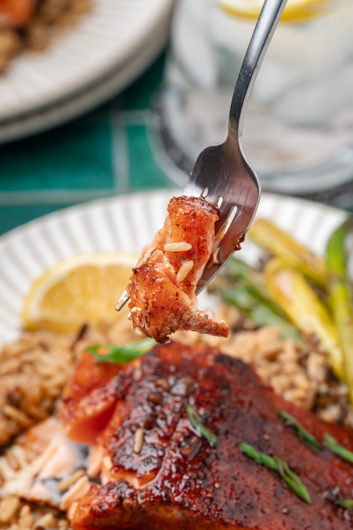fork holding a flaky bite of pan seared salmon with caramelized glaze and tender interior