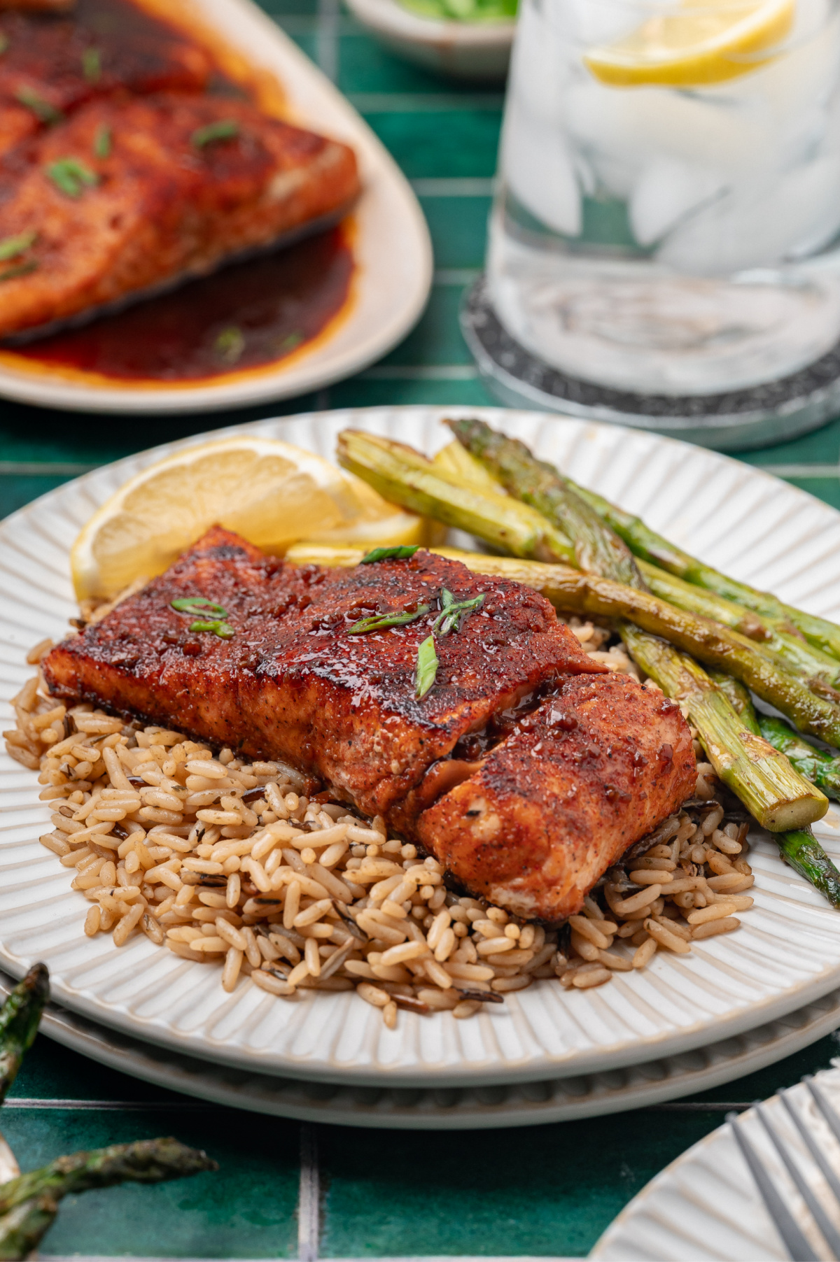pan seared salmon with a glossy glaze served over rice with roasted asparagus and lemon
