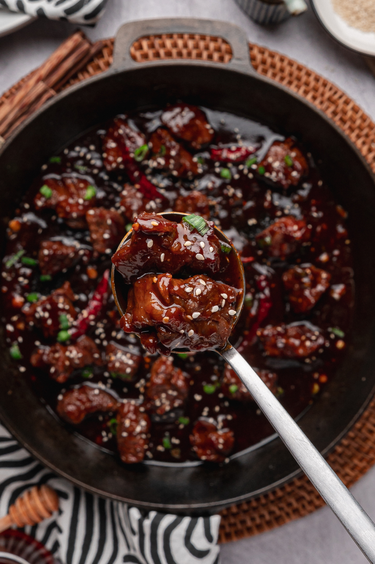 gochujang steak bites in skillet with sesame seeds green onions and dried chiles