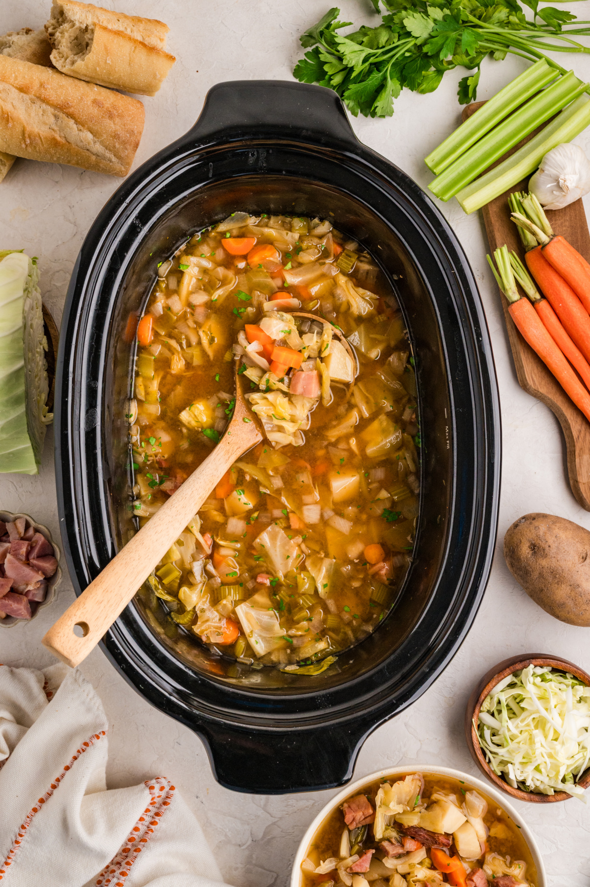 Ham cabbage soup cooking in a slow cooker with cabbage, potatoes, carrots, and ham in broth