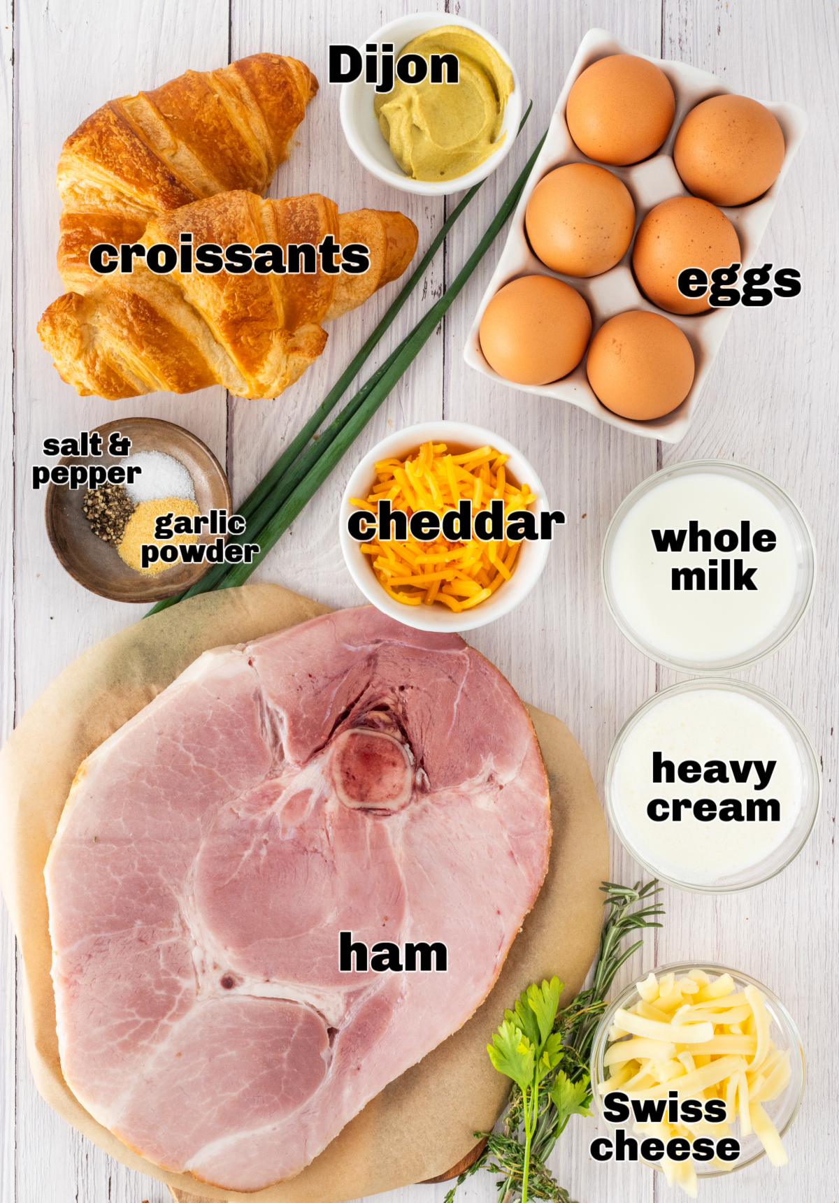ingredients for ham and cheese croissant breakfast bake including croissants, ham steak, eggs, milk, cream, shredded cheese, Dijon mustard, and chives