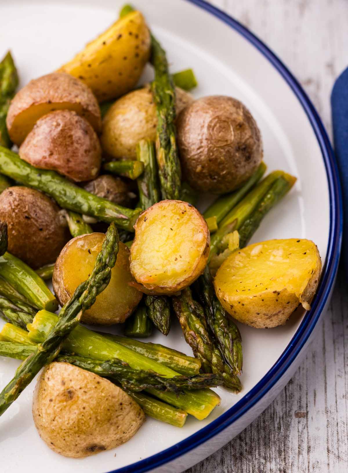 lemon garlic roasted potatoes and asparagus close-up on plate, showing crisp edges on potatoes and tender asparagus