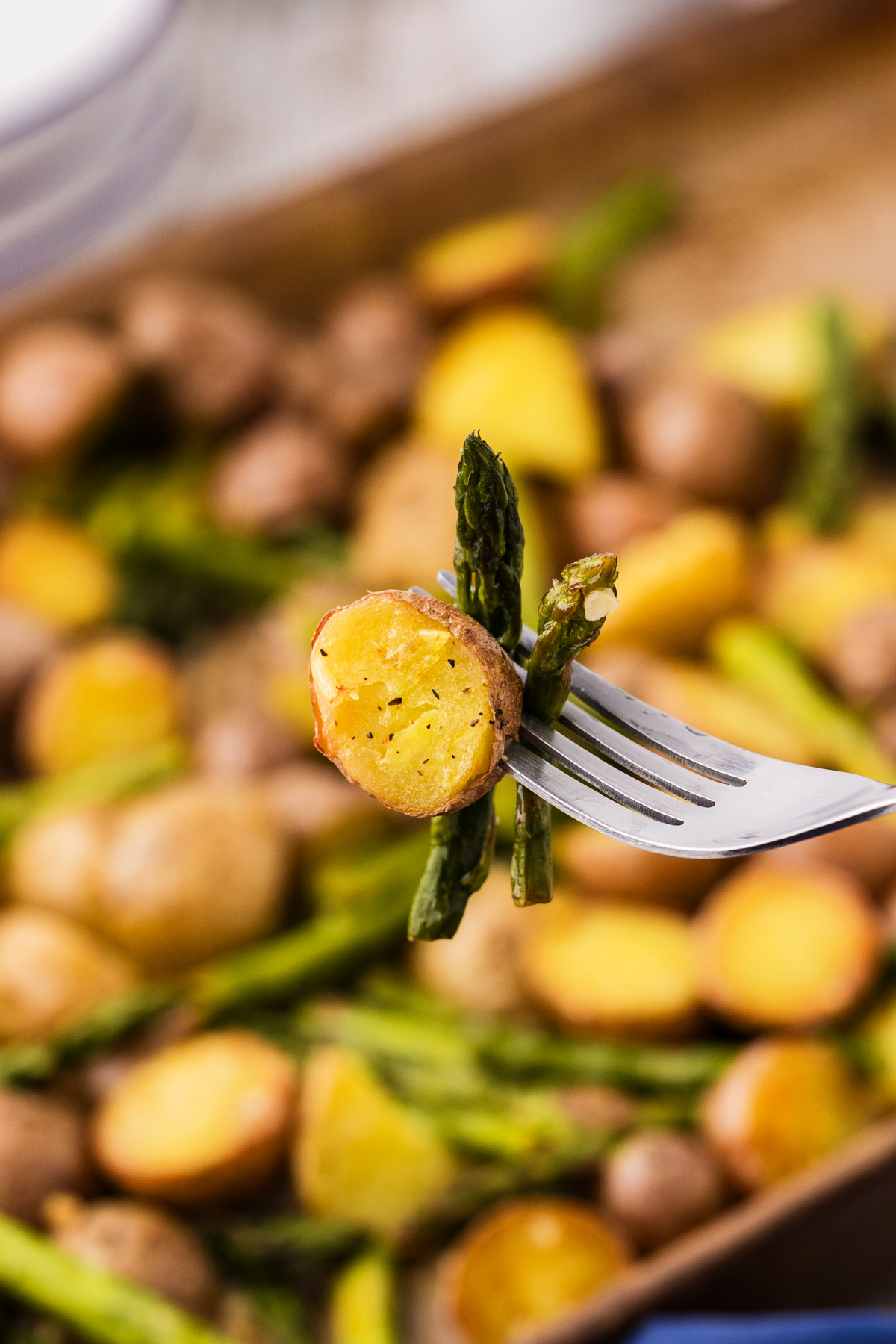 fork holding roasted baby potatoes and asparagus, showing crisp edges and tender centers with lemon garlic flavor