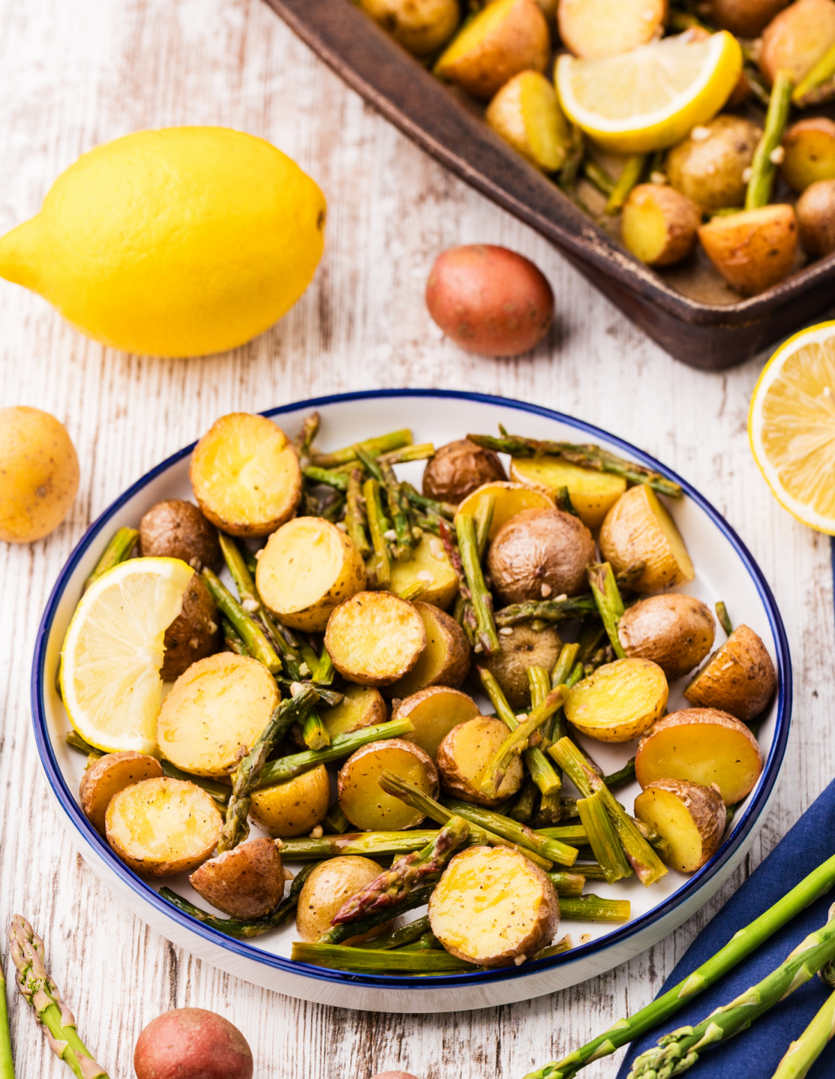 lemon garlic roasted potatoes and asparagus served on plate with lemon wedge, golden baby potatoes and tender asparagus
