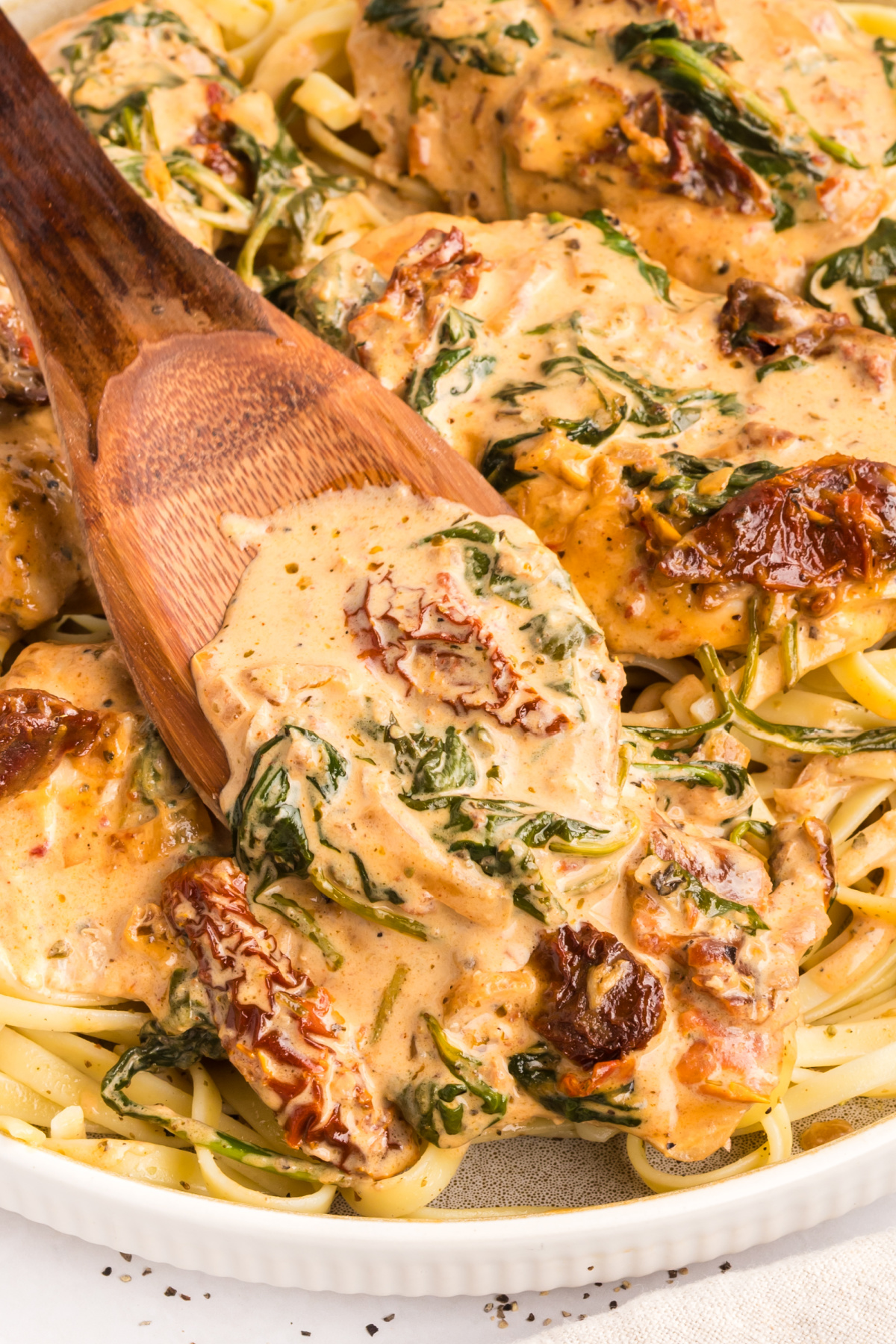 Marry Me Tuscan Chicken served over pasta with creamy parmesan sauce, sun-dried tomatoes, and spinach