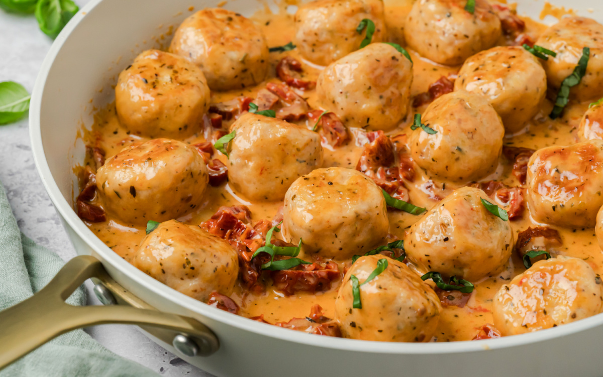Marry me chicken meatballs simmering in a creamy sun-dried tomato Parmesan sauce in a one-pan skillet