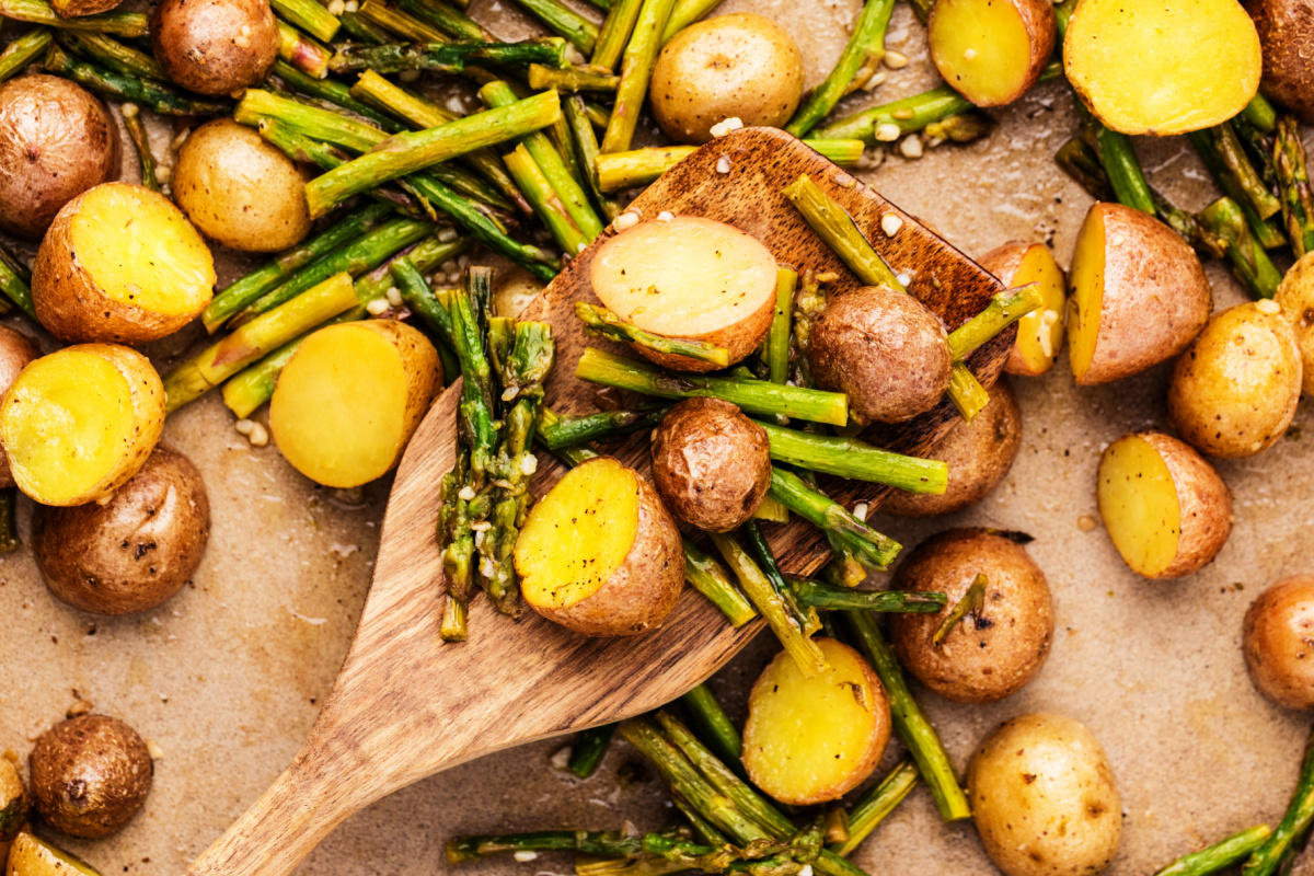 roasted potatoes and asparagus close-up with lemon garlic, halved baby potatoes and roasted asparagus on wooden spatula