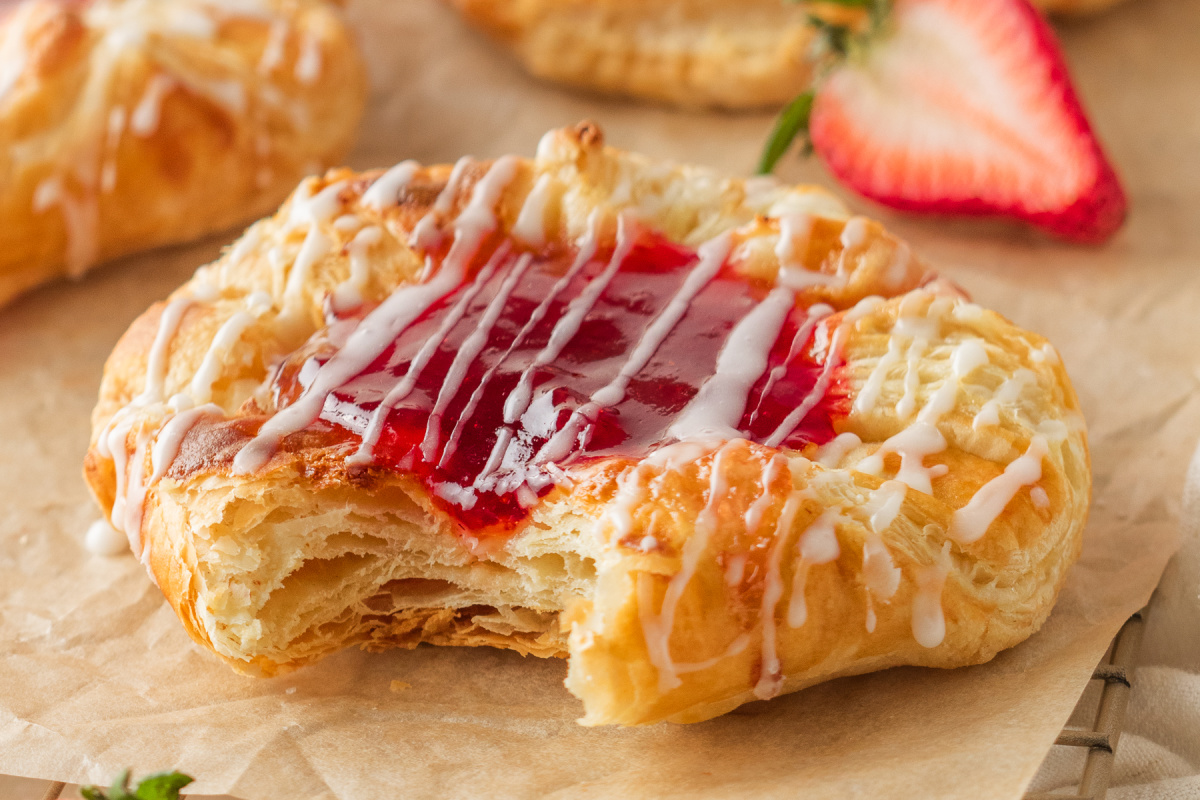 strawberry cream cheese danish with a bite showing flaky puff pastry layers and jam center