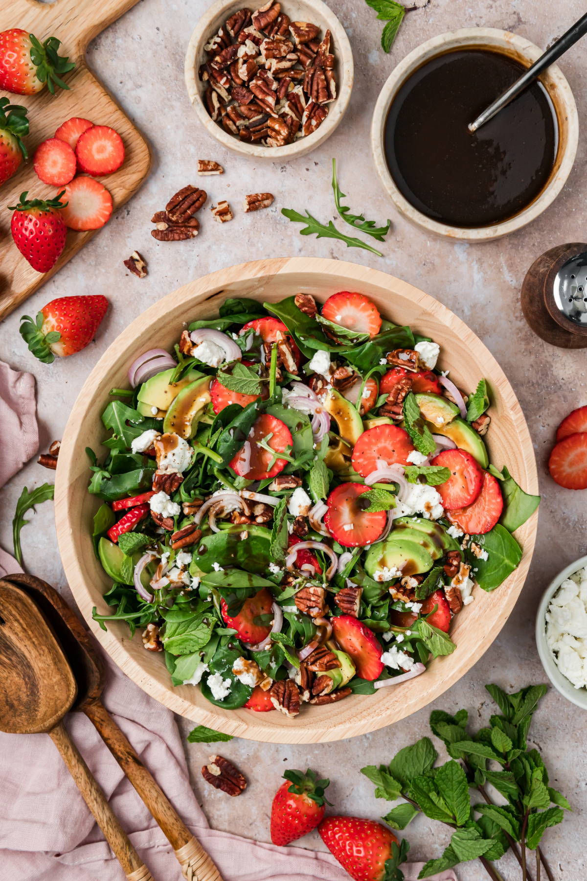 Strawberry goat cheese salad with avocado, pecans, mint, and balsamic vinaigrette in a wooden bowl