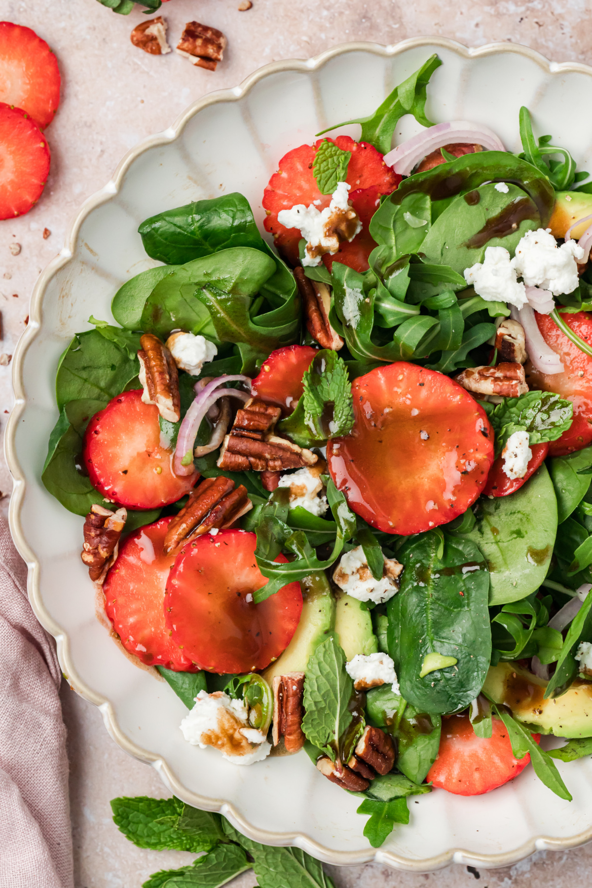 Strawberry spinach goat cheese salad with avocado, pecans, mint, and balsamic vinaigrette in a serving bowl