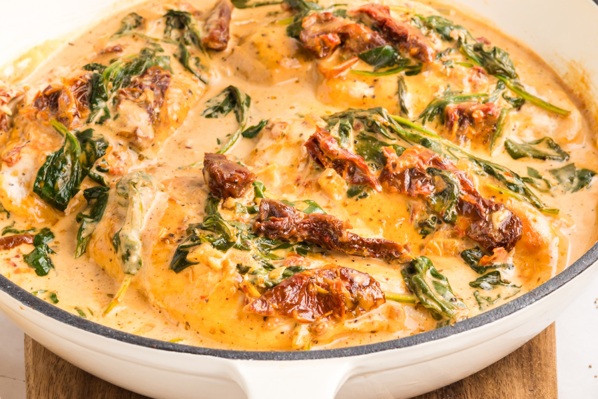 creamy tuscan chicken in skillet with sun-dried tomatoes and spinach in parmesan sauce