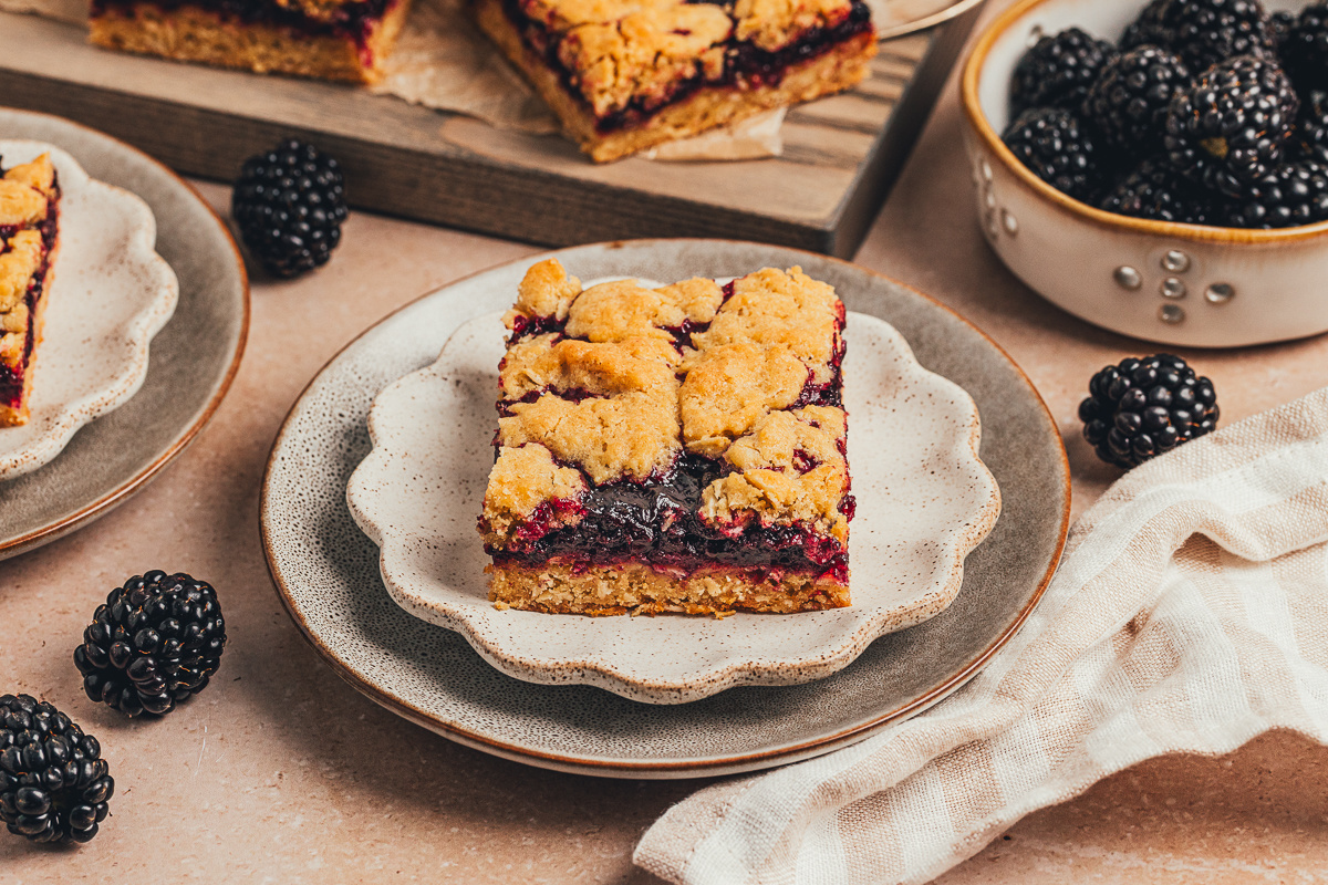 blackberry crumble bar on a plate with oat topping and thick blackberry filling