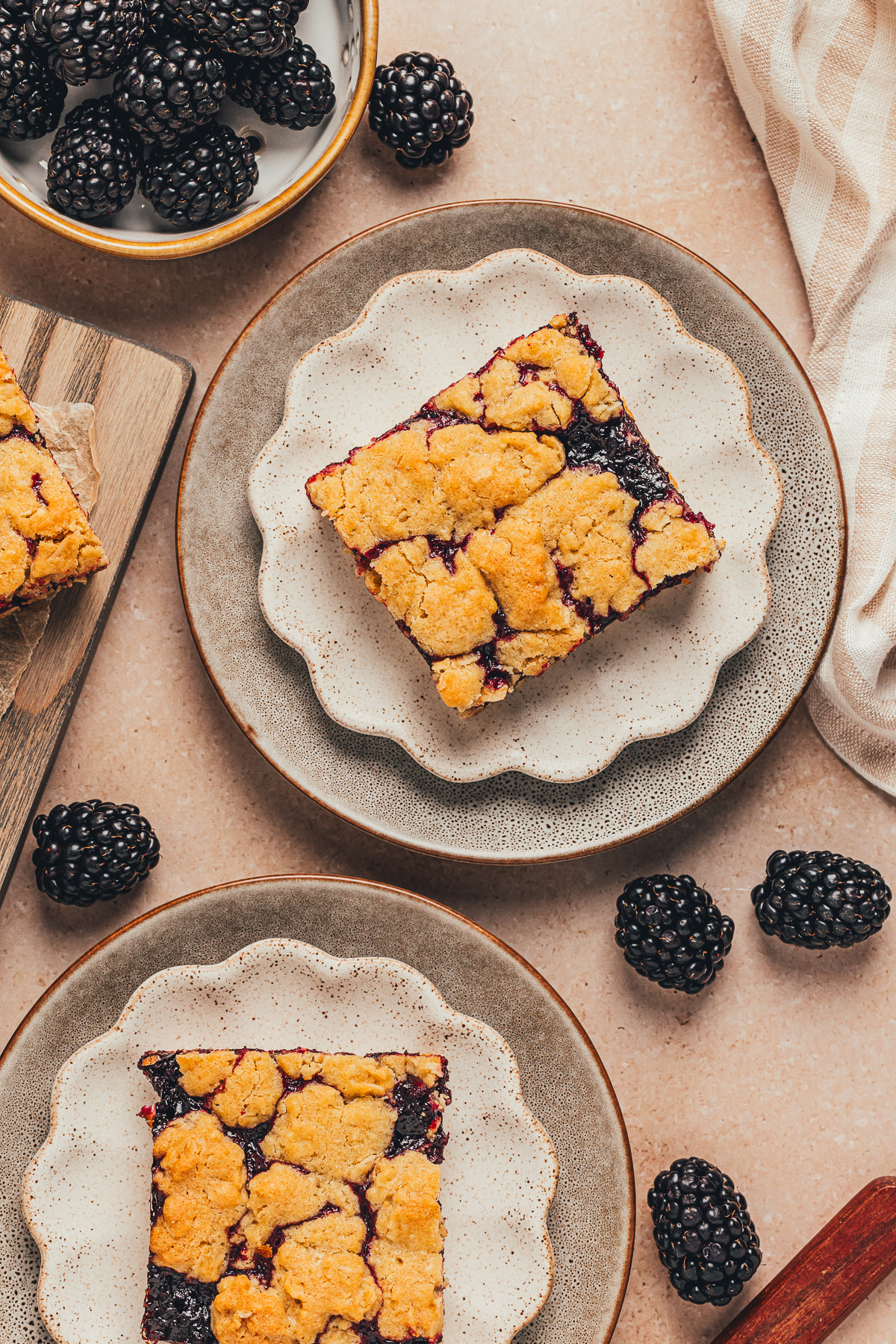 blackberry crumble bars served on plates with fresh blackberries around