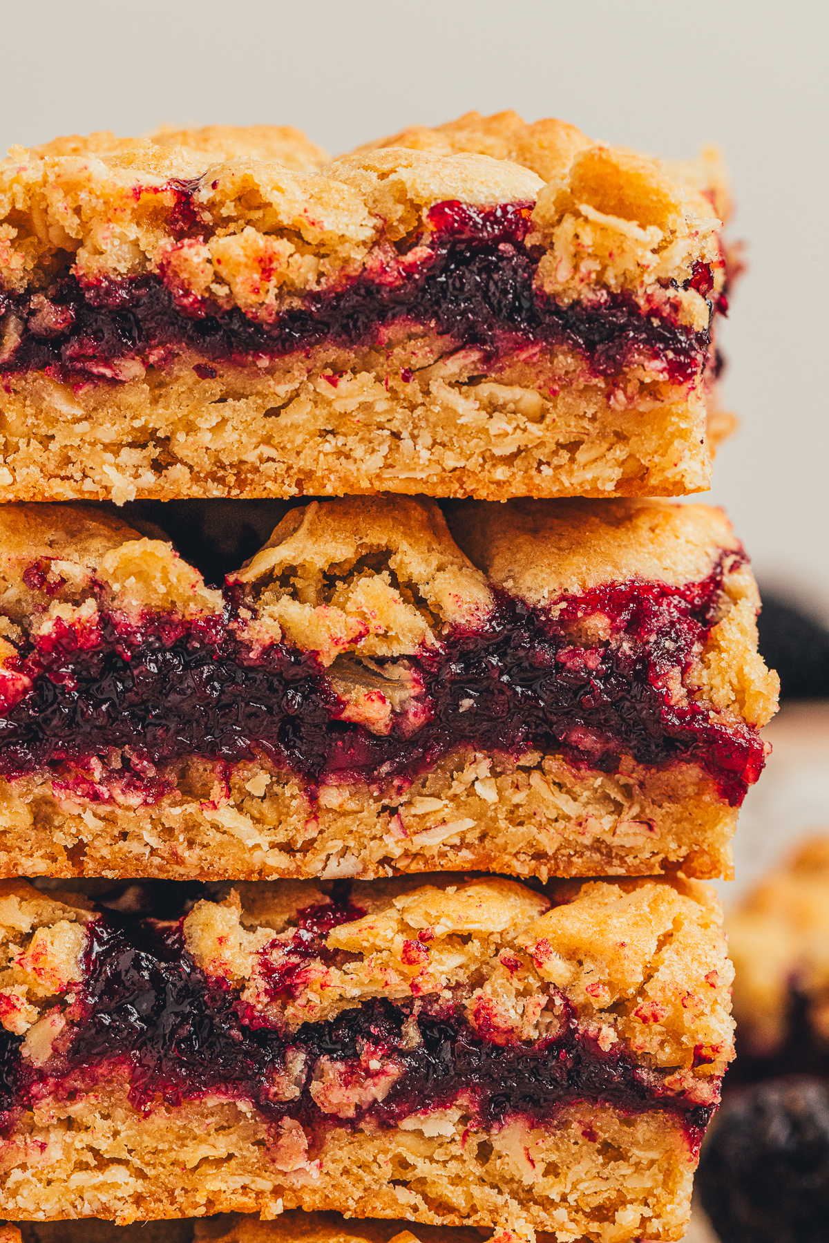 blackberry crumble bars stacked showing thick blackberry layer and oat crumble topping