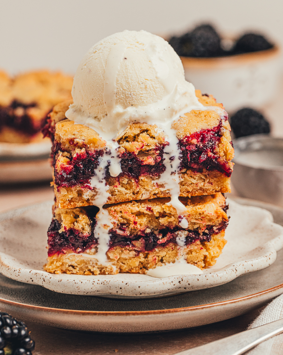 blackberry crumble bars topped with vanilla ice cream and blackberry filling