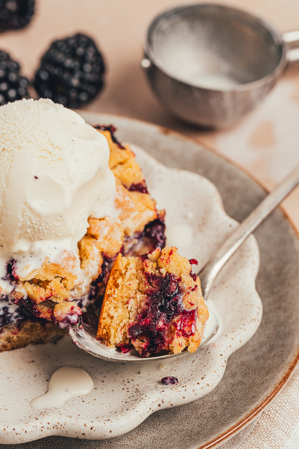 bite of blackberry oat crumble bar with vanilla ice cream and spoon