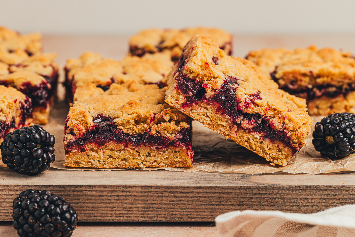 blackberry oat crumble bars cut into squares with fresh blackberries on the side