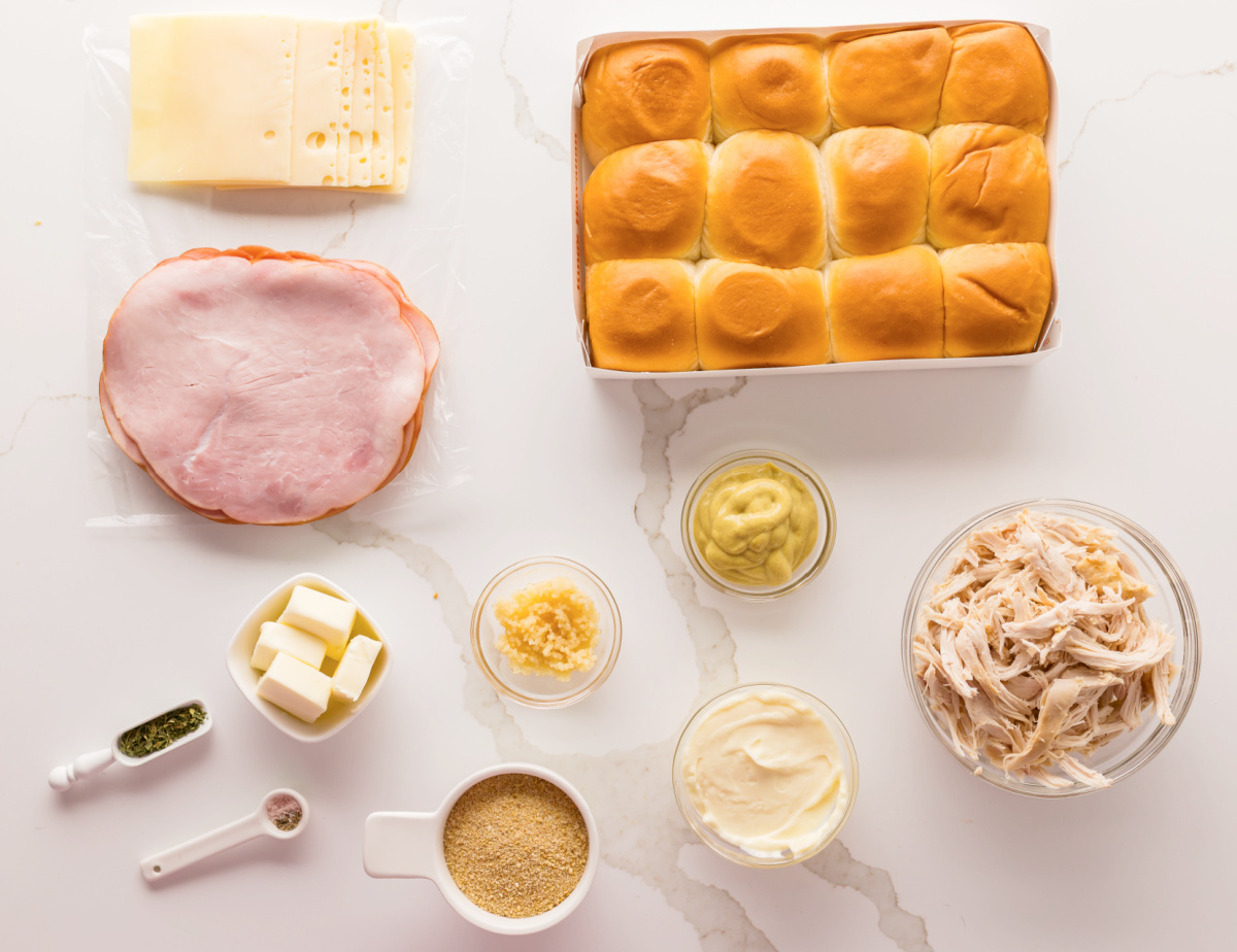 Ingredients for chicken cordon bleu sliders including Hawaiian rolls, ham, Swiss cheese, shredded chicken, Dijon mustard, mayonnaise, garlic, butter, and panko breadcrumbs