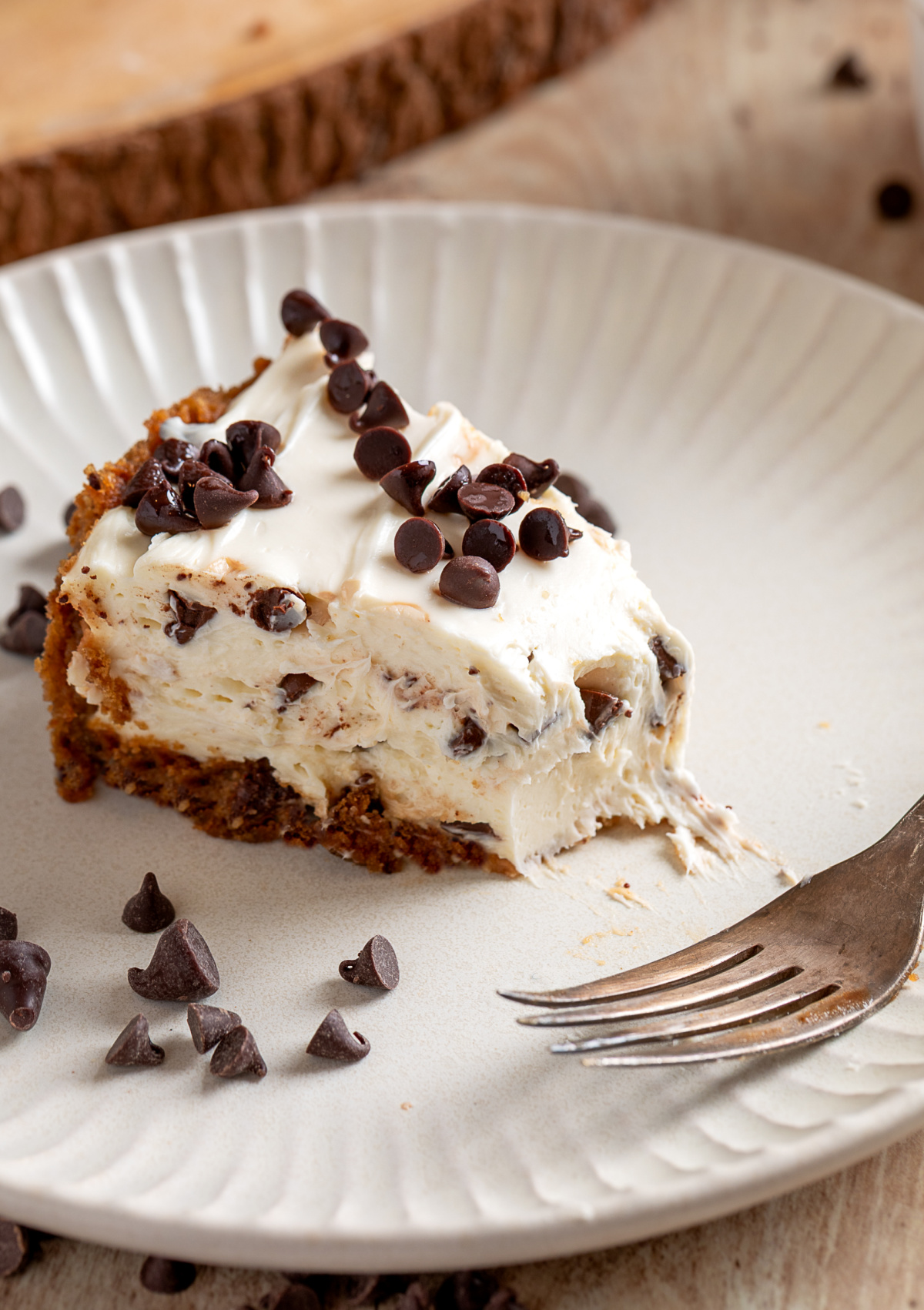 slice of chocolate chip cookie dough crust cheesecake with creamy no-bake filling on a plate