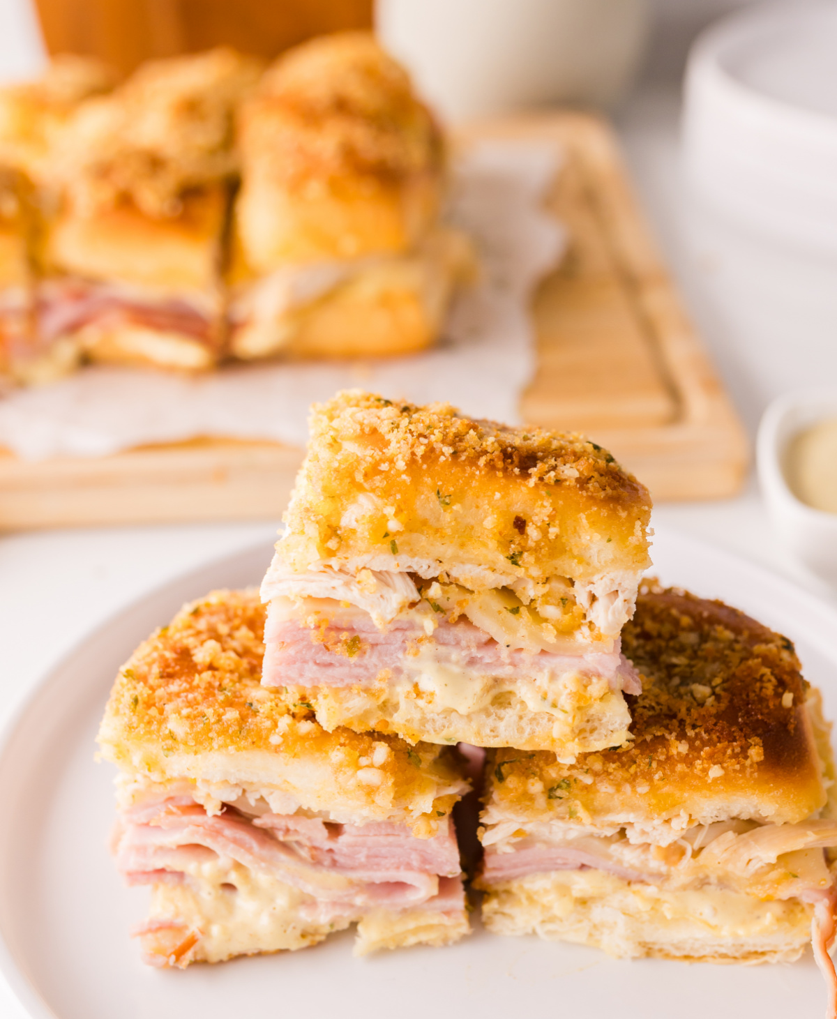 Stacked baked cordon bleu slider squares showing layers of ham, melted Swiss cheese, and shredded chicken with crispy topping
