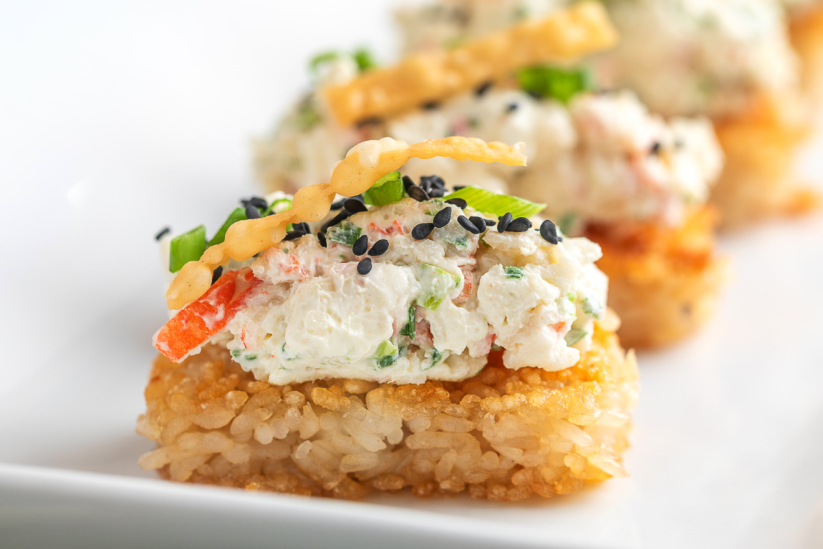 Crispy Rice Crab Rangoon Bites close up with creamy crab filling, sesame seeds, green onions, and wonton strip