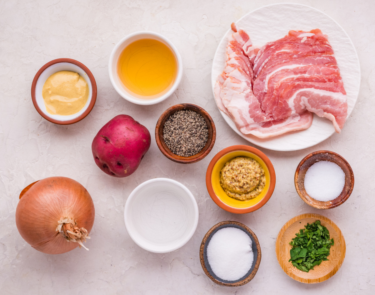 German potato salad ingredients including red potatoes, bacon, onion, apple cider vinegar, Dijon and whole grain mustard, and herbs