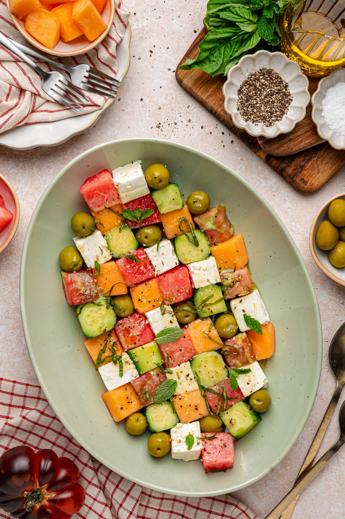 Greek mosaic salad with watermelon, feta, cucumber, olives, and herbs on a platter