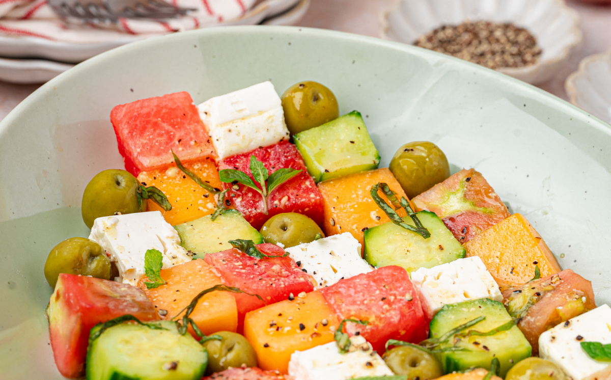 Greek mosaic salad with watermelon, feta, cucumber, olives, and herbs in a serving bowl