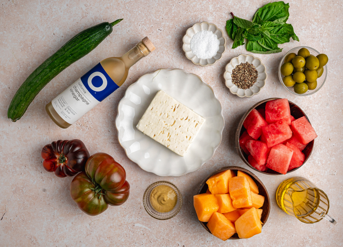 ingredients for Greek-style salad with watermelon, cantaloupe, feta, cucumber, olives, and herbs