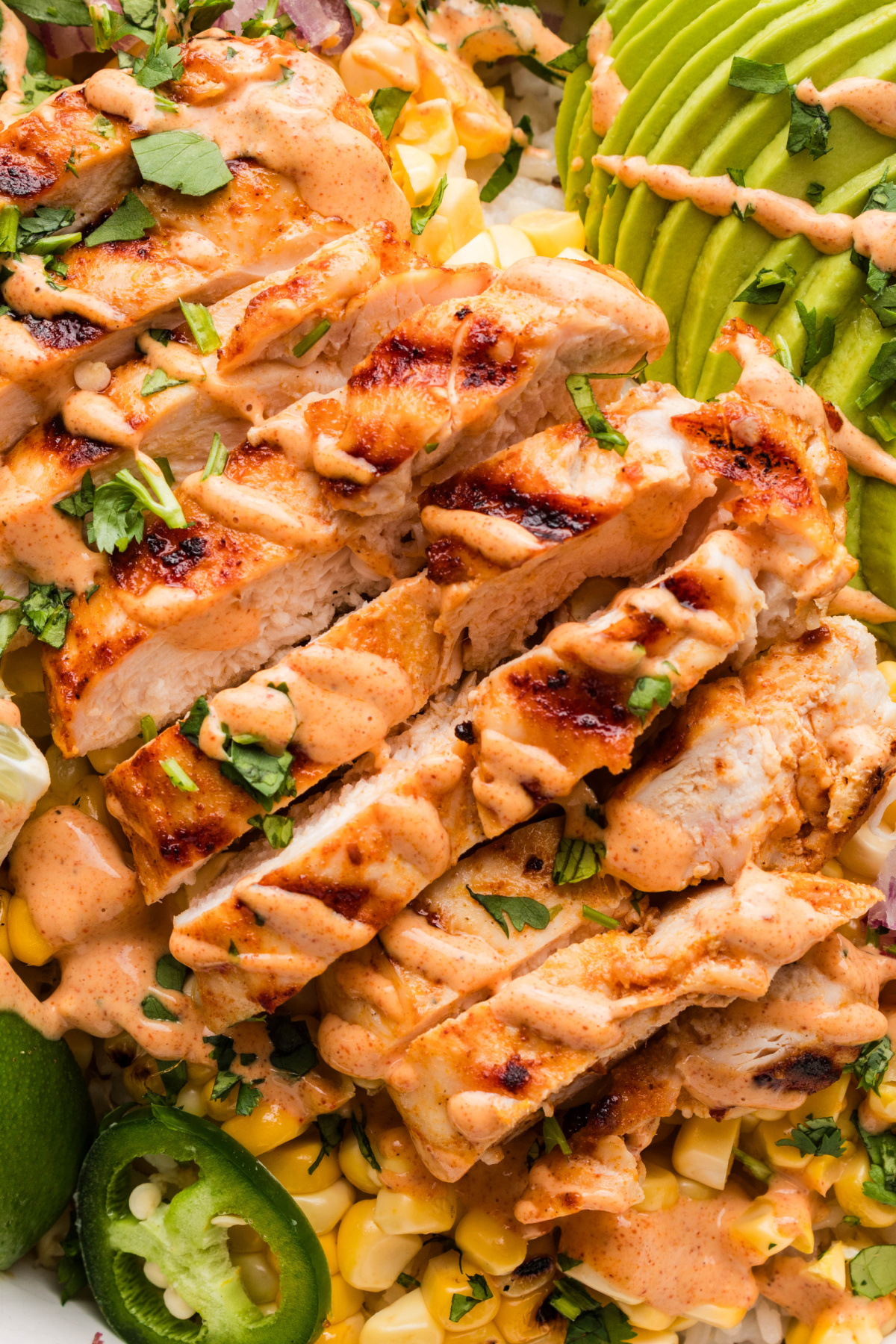 grilled chicken slices with charred corn, jalape&ntilde;os, avocado, and creamy elote-style sauce over rice