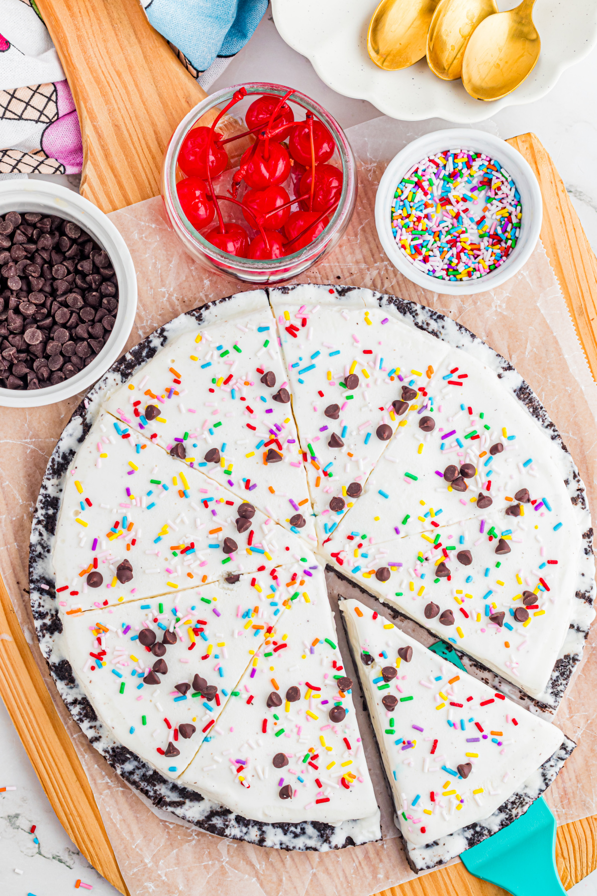 ice cream pizza sliced into wedges with Oreo crust, sprinkles, and chocolate chips